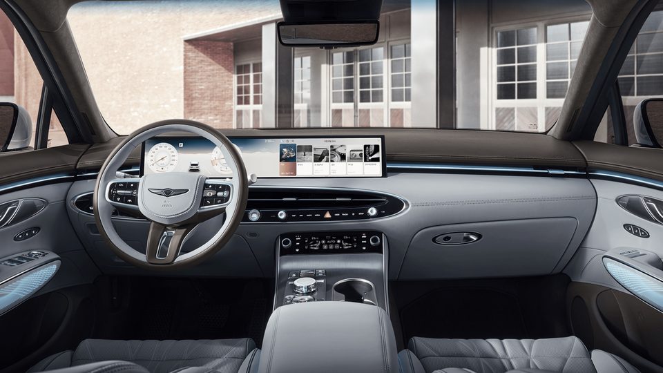 Front cabin viewed from the rear, showing the dashboard, steering wheel, display and center console.