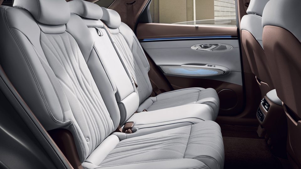 Side view of rear bench seats with pale quilted upholstery and brown/gray door trim.