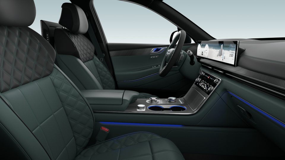 Side view of front cabin with quilted green/black seats, steering wheel, wide display and center console.
