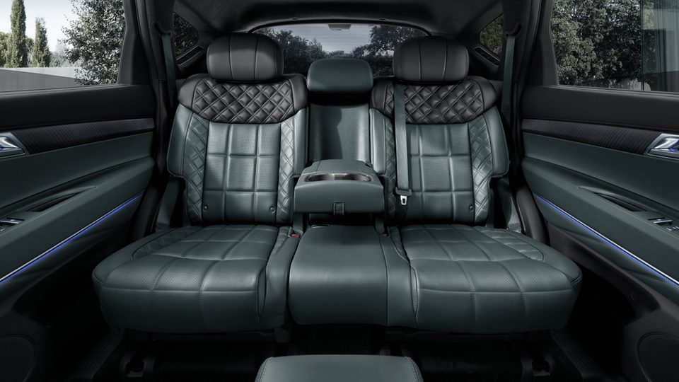 Rear bench with quilted green/black leather, center armrest and blue ambient lighting.