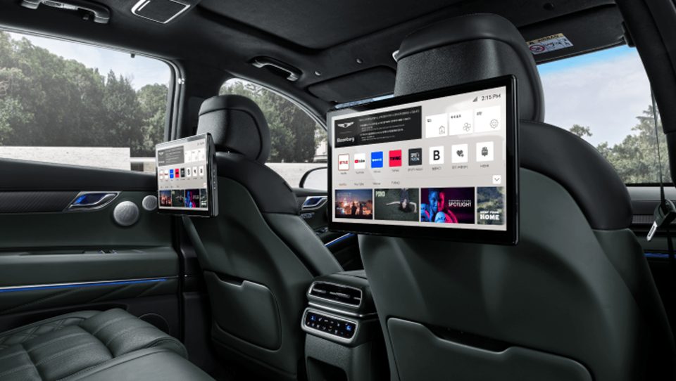 Two separate rear entertainment screens mounted behind front seat headrests; screen interfaces visible.